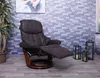 A brown recliner chair with its footrest extended, placed in a room with a stone-tiled wall and wooden floor. There are decorative lanterns with candles on the floor next to the chair. Produktbild-Vorschau