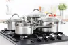 A set of stainless steel pots and pans on a gas stovetop in a kitchen. Anteprima dell’immagine prodotto
