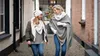 Two women walking down a narrow street, one wearing a beige scarf. Produktbild-Vorschau