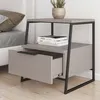 A modern nightstand with a drawer and an open shelf, next to a bed. Voir les images du produit