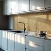 A modern kitchen with light gray cabinets and a gold backsplash. A black faucet is installed over a sink, and a pot sits on an induction stovetop. Podgląd zdjęcia produktu