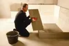 A man is tiling a floor in a room. Produktbild-Vorschau