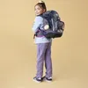 A young girl wearing a backpack and looking over her shoulder. Náhľad obrázku produktu