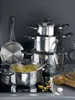 A collection of stainless steel pots and pans are arranged on a black stovetop. Produktbild-Vorschau