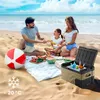 A family is having a picnic on the beach with a cooler box, food, and a beach ball. Anteprima dell’immagine prodotto