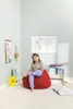 A young girl sits on a red beanbag chair in a room with a world map on the wall. Náhled obrázku produktu