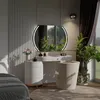 A bedroom vanity area with a mirror, stool, and dresser, decorated with plants and soft lighting. Produktbild-Vorschau