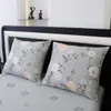 Two floral patterned pillows on a bed with a headboard and a shelf with figurines above. Produktbild-Vorschau
