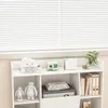 A white shelf unit filled with decorative items and books, placed in front of white blinds. Podgląd zdjęcia produktu