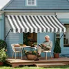 An elderly man sits on a patio reading a magazine under a striped awning. Náhled obrázku produktu
