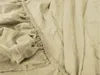 A close-up view of a beige fitted sheet, showing the elasticized edge and fabric texture. Produktbild-Vorschau