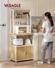 A woman is standing next to a kitchen baker's rack filled with kitchen appliances and pantry items. Náhled obrázku produktu