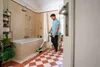 A man is cleaning a bathroom floor with a cordless floor cleaner. Anteprima dell’immagine prodotto