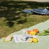 A picnic scene with food, flowers, and a portable fan. Produktbild-Vorschau