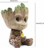 A decorative planter shaped like Baby Groot from Guardians of the Galaxy, holding a small yellow bird. Produktbild-Vorschau