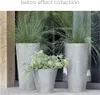 Three concrete-effect planters with different types of plants are displayed on a patio or walkway. Produktbild-Vorschau