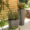 Two planters with plants on a patio next to a wooden fence. Produktbild-Vorschau