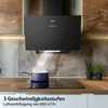 A black range hood is shown above a stovetop with a pot steaming, in a modern kitchen setting. Voir les images du produit