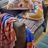 A cozy arrangement of pillows and a throw blanket on a chair. Produktbild-Vorschau