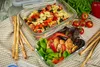 Two glass food containers filled with pasta salad and chicken salad, placed on a checkered cloth with breadsticks and tomatoes in the background. Produktbild-Vorschau