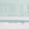 A close-up view of text on a light blue background, with a white ribbon detail across the middle. Produktbild-Vorschau