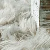 A close-up of a fluffy gray rug next to a distressed wooden frame. Produktbild-Vorschau