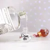A clear bottle is pouring liquid into a small glass ornament with the words 'Drink Me' on it. Another ornament is in the background. Anteprima dell’immagine prodotto