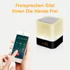 A person is holding a smartphone displaying a call screen, next to a cube-shaped speaker with a light and a digital clock. Produktbild-Vorschau