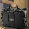 A person is holding a black transport case with wheels. Produktbild-Vorschau
