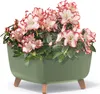 A potted plant with pink and white flowers in a green planter with wooden legs. Voir les images du produit