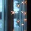 A string of star-shaped LED lights hanging in front of a window. Podgląd zdjęcia produktu