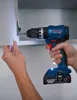 A person is using a Bosch cordless drill to attach a cabinet hinge. Podgląd zdjęcia produktu