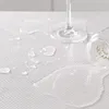 A close-up shot of a white, textured surface with water droplets and a glass. Voir les images du produit
