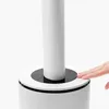 A close-up shot of the base of a white cylindrical air purifier with a hand touching its surface. Podgląd zdjęcia produktu