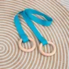 A pair of blue gymnastic rings with wooden handles lies on a circular patterned rug. Náhľad obrázku produktu