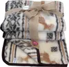 A stack of folded blankets tied with a ribbon and a small decorative flower. Produktbild-Vorschau