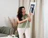 A woman is holding a mop in a living room setting. Produktbild-Vorschau