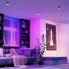 A modern living room with a sofa, bookshelf, and artwork, illuminated by purple and pink smart lights. Produktbild-Vorschau