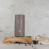 A taupe electric coffee grinder and a shot of espresso are displayed on a wooden board with coffee beans scattered around. Náhľad obrázku produktu