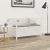 A white storage bench with a gray cushion is placed in a room with a small side table and a floor lamp. Náhled obrázku produktu