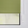 A close-up view of a green roller blind attached to a window frame, with a white pull cord and bracket visible. Náhled obrázku produktu