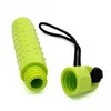 A bright green, textured cylindrical object, possibly a dog toy or a chew toy, is shown with its cap detached. The cap is connected to the main body by a black cord. The background is plain white. Produktbild-Vorschau