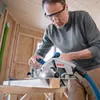 A man is using a Bosch circular saw to cut a piece of wood in a workshop. Podgląd zdjęcia produktu