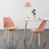 Two pink chairs are placed around a white table in a room. Voir les images du produit