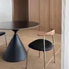 A modern dining set with a black round table and black chairs with wooden accents, set in a room with wooden cabinetry and a light brown rug. Produktbild-Vorschau