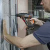 A person is using a cordless hammer drill to drill into a wall. Produktbild-Vorschau
