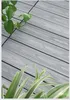 A close-up of grey wood-like decking with two types of plants. Náhled obrázku produktu