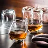 Several whiskey glasses are arranged on a reflective surface, with some containing amber liquid. Podgląd zdjęcia produktu