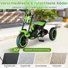 A green and black children's tricycle is shown outdoors on a paved surface, with various road surface examples at the bottom. Produktbild-Vorschau