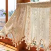 A close-up view of a lace curtain with tassels hanging in a window. Anteprima dell’immagine prodotto